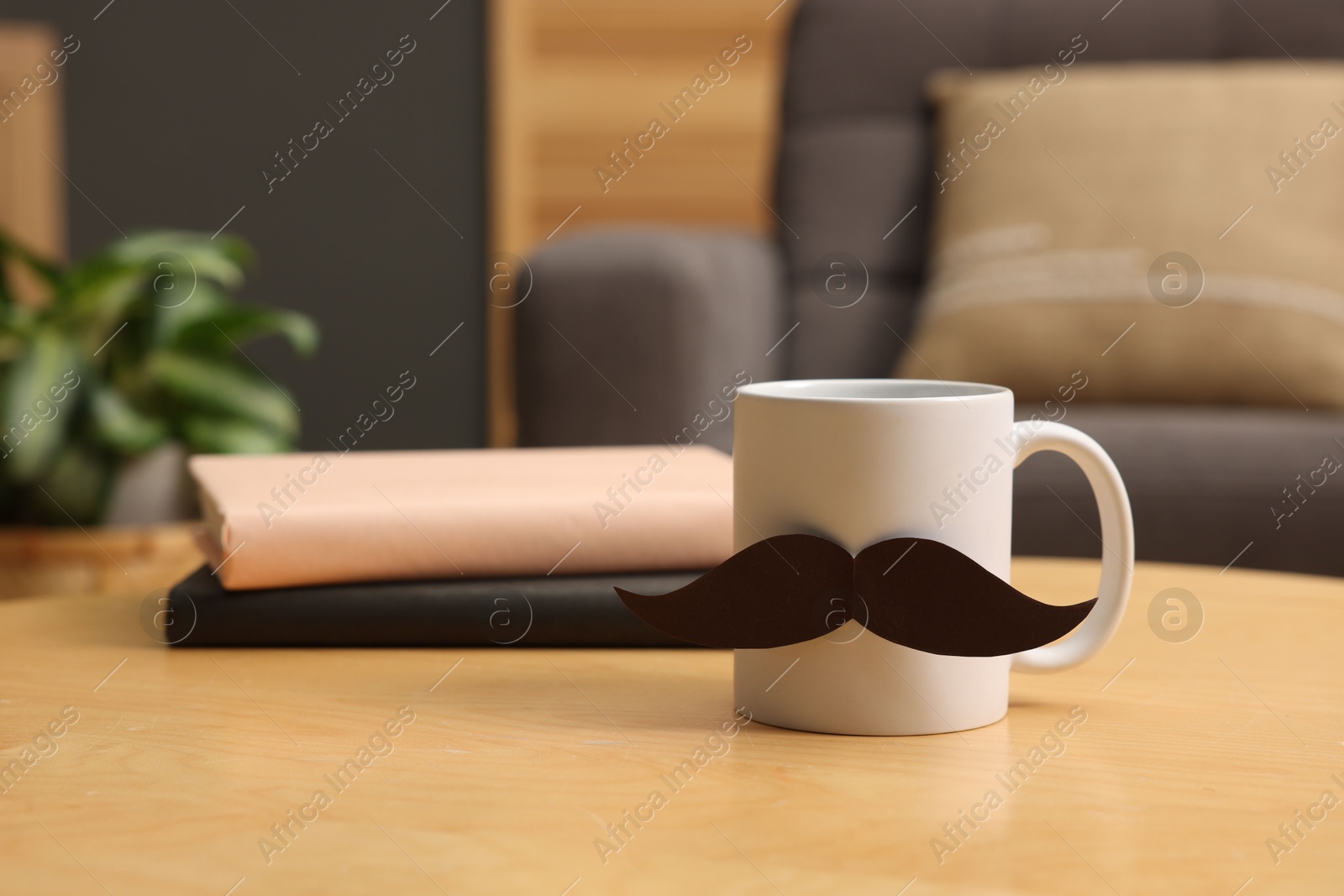 Happy Father's Day. Cup with paper moustache and books on wooden table indoors Photo of Happy Father's Day. Cup with paper moustache and books on wooden table indoors