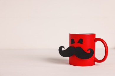 Photo of Happy Father's Day. Cup with paper face on white wooden table, space for text