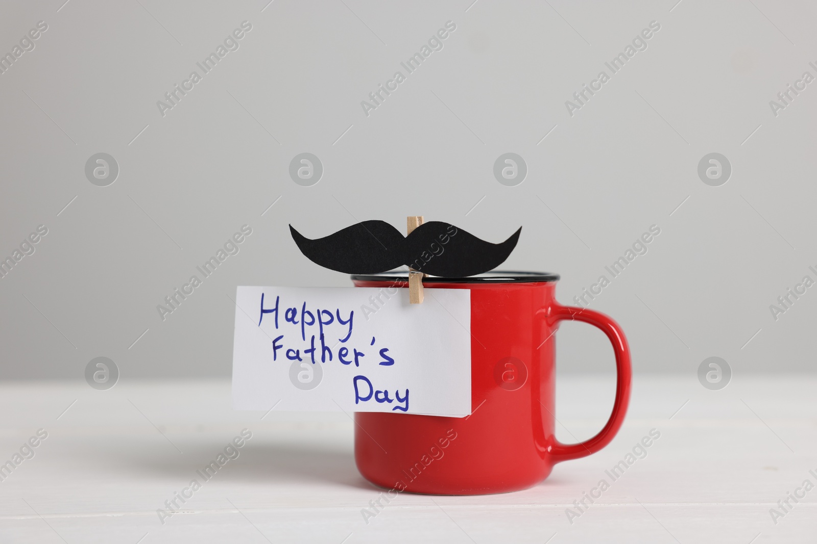 Happy Father's Day. Cup with paper moustache and card on white wooden table Photo of Happy Father's Day. Cup with paper moustache and card on white wooden table