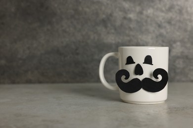 Photo of Happy Father's Day. Cup with paper face on light grey table, space for text