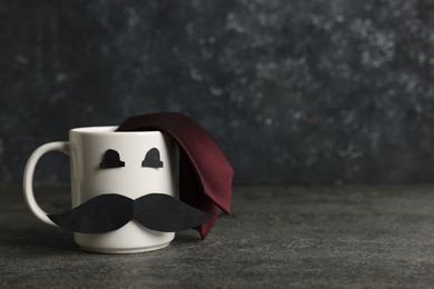 Photo of Happy Father's Day. Cup with paper face and tie on black table, space for text