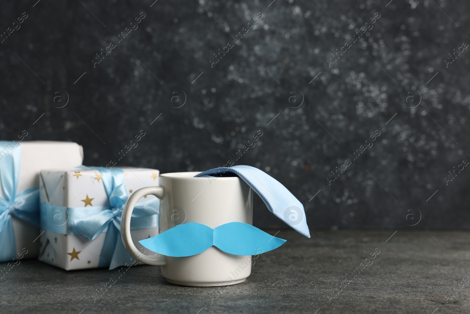 Happy Father's Day. Cup with paper moustache, gift boxes and tie on black table, space for text Photo of Happy Father's Day. Cup with paper moustache, gift boxes and tie on black table, space for text