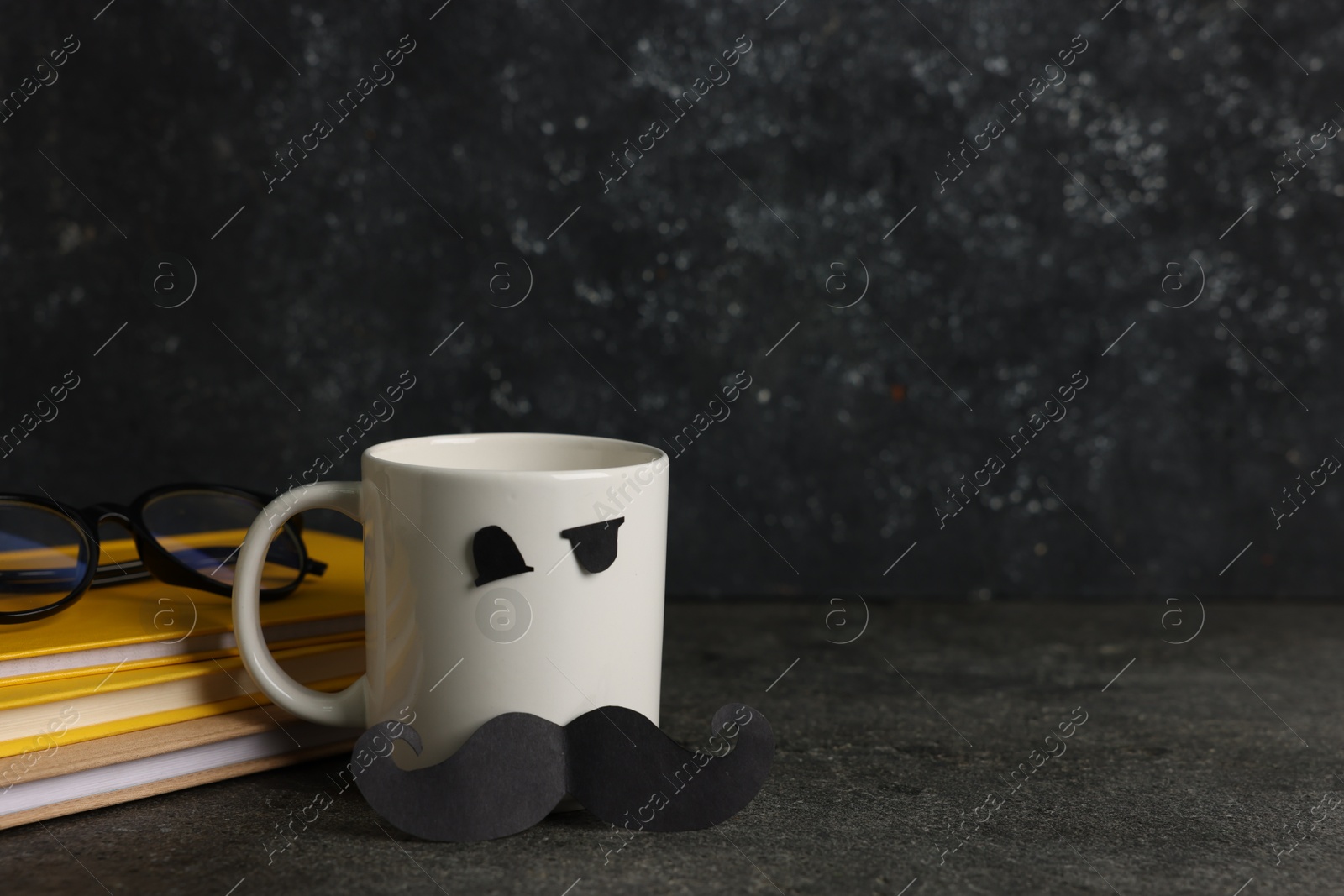 Happy Father's Day. Cup with paper face, books and glasses on black table, space for text Photo of Happy Father's Day. Cup with paper face, books and glasses on black table, space for text