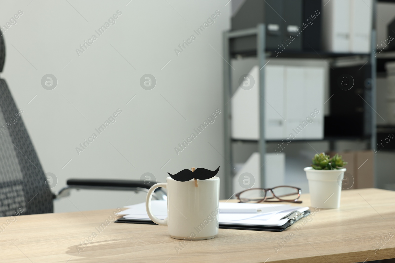 Happy Father's Day. Cup with paper moustache and clipboard on wooden table Photo of Happy Father's Day. Cup with paper moustache and clipboard on wooden table