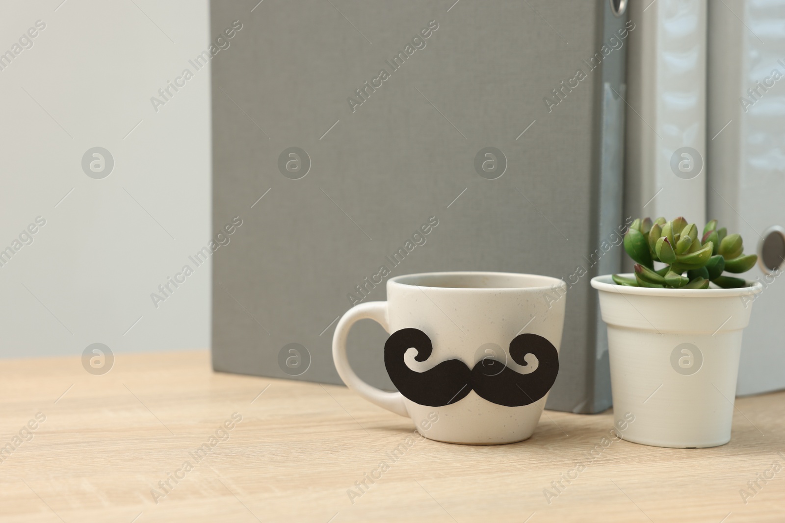Happy Father's Day. Cup with paper moustache and houseplant on wooden table, space for text Photo of Happy Father's Day. Cup with paper moustache and houseplant on wooden table, space for text