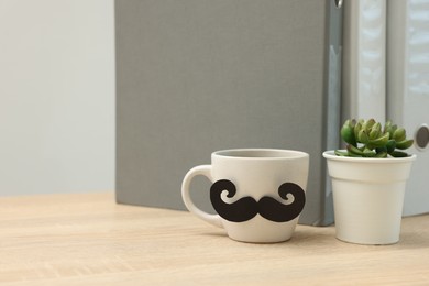 Photo of Happy Father's Day. Cup with paper moustache and houseplant on wooden table, space for text