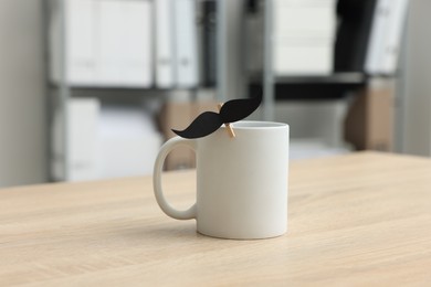Photo of Happy Father's Day. Cup with paper moustache on wooden table
