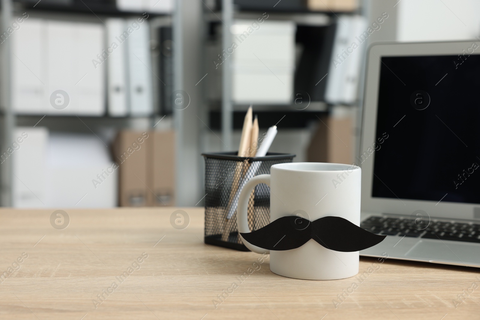 Happy Father's Day. Cup with paper moustache and laptop on wooden table, space for text Photo of Happy Father's Day. Cup with paper moustache and laptop on wooden table, space for text