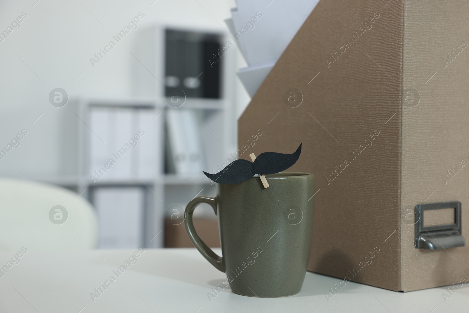 Happy Father's Day. Cup with paper moustache on white table indoors Photo of Happy Father's Day. Cup with paper moustache on white table indoors