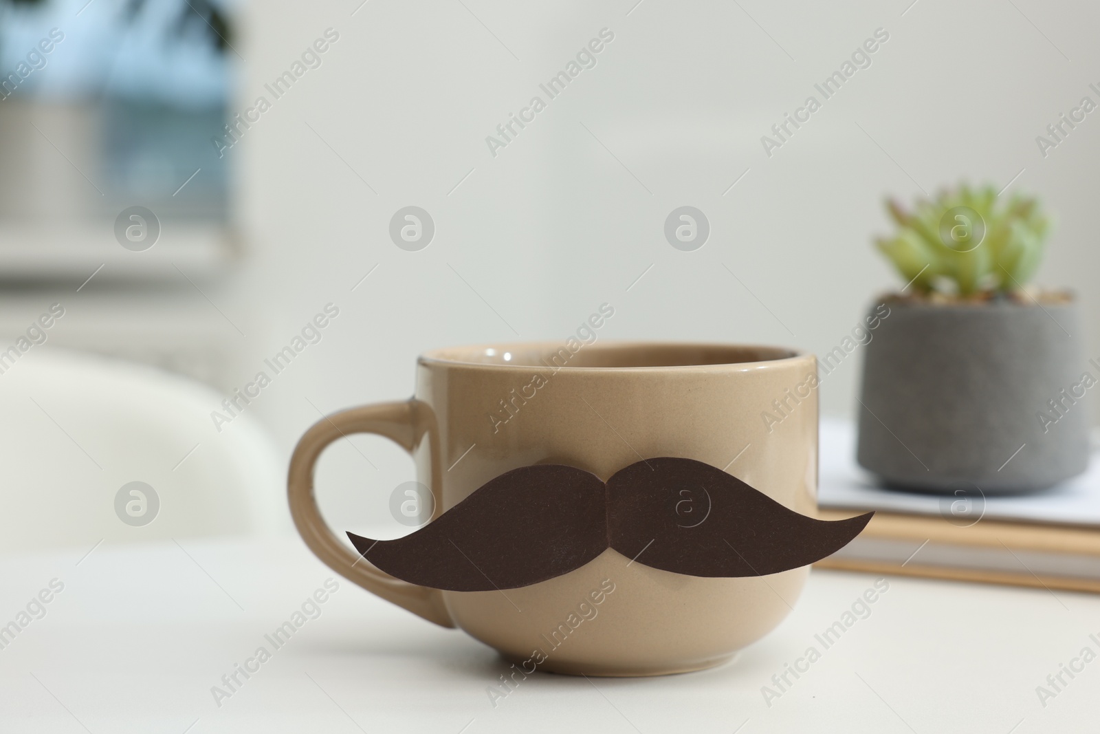 Happy Father's Day. Cup with paper moustache and books on white table indoors, closeup Photo of Happy Father's Day. Cup with paper moustache and books on white table indoors, closeup