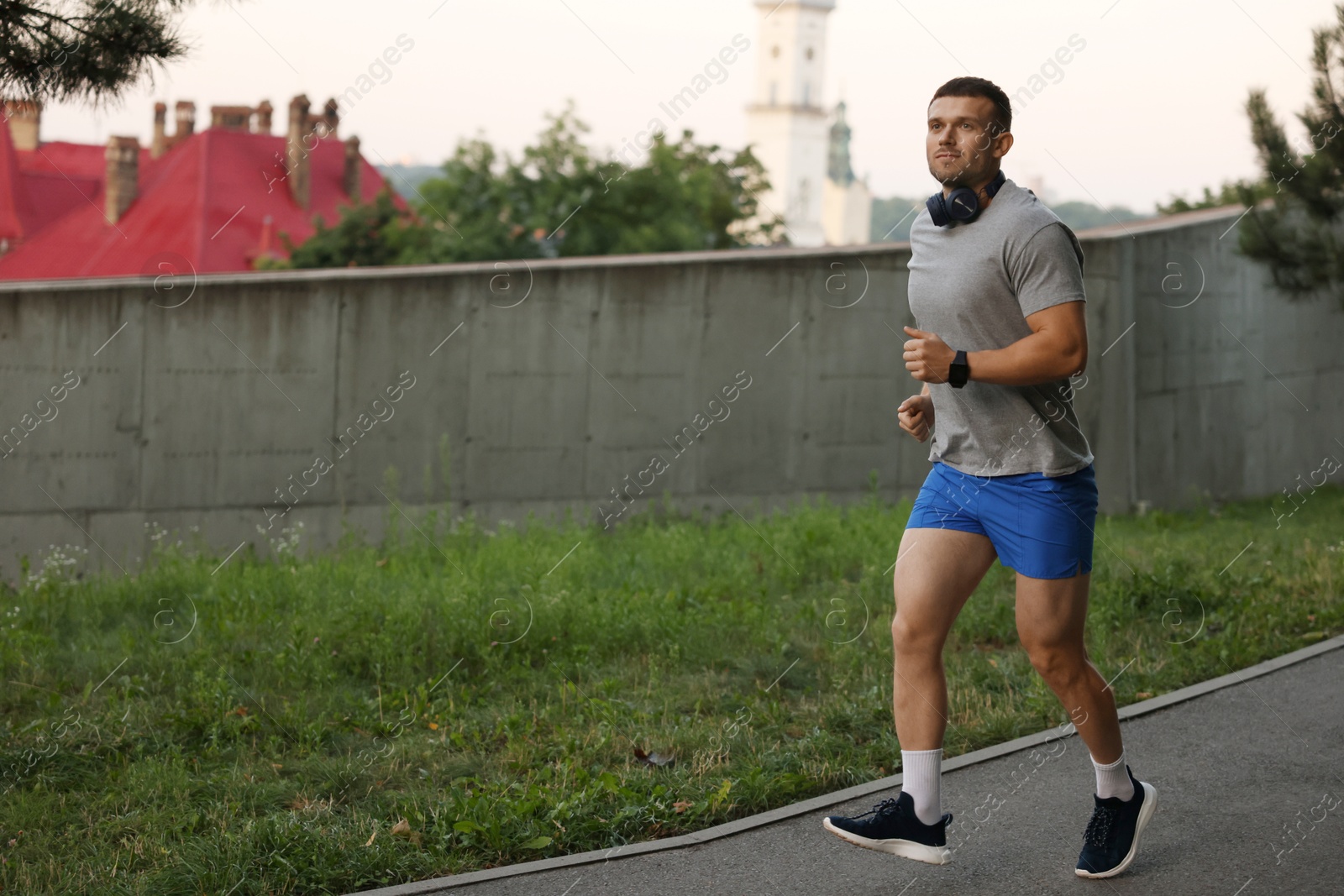 Athletic young man in sportswear running outdoors, space for text Photo of Athletic young man in sportswear running outdoors, space for text