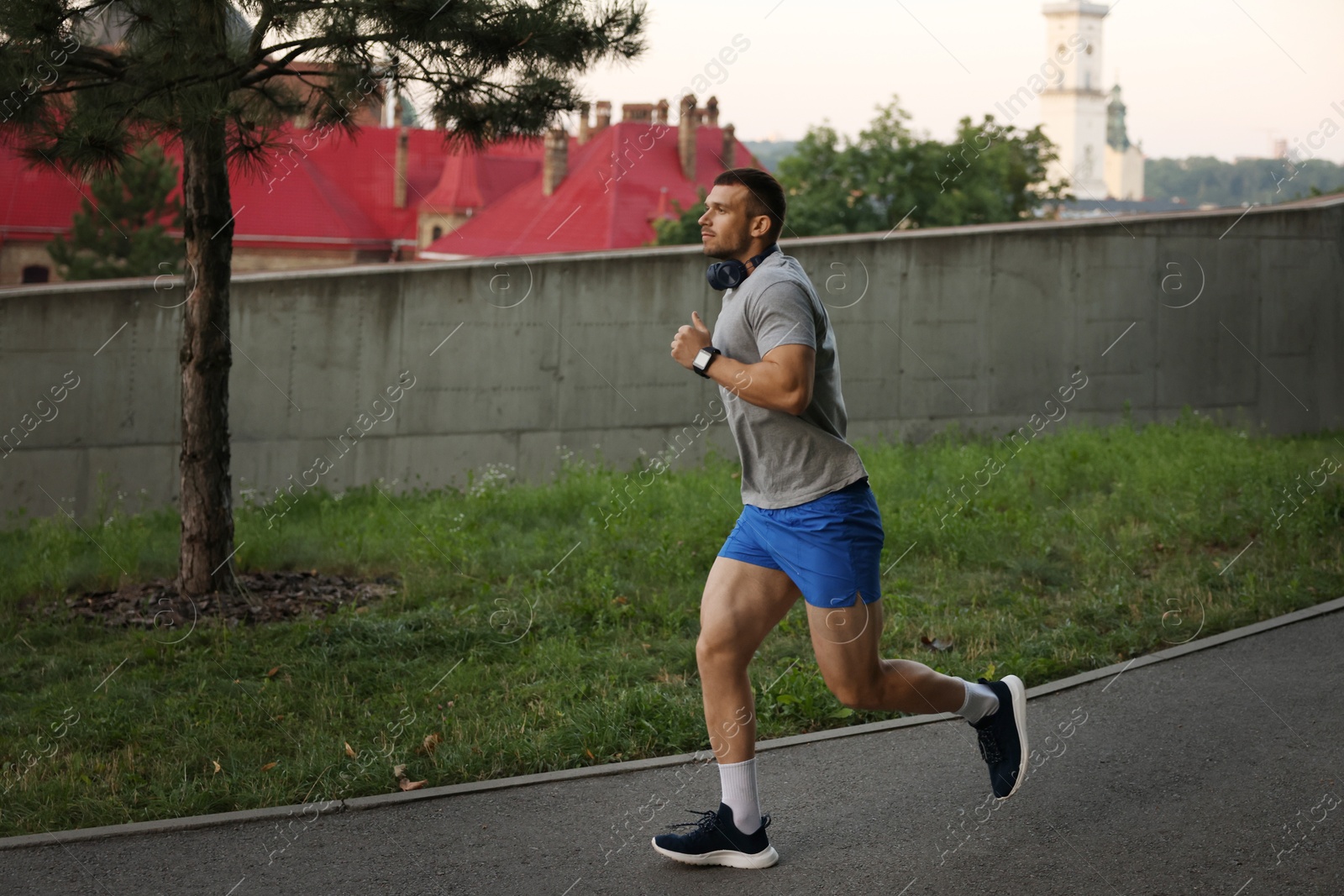 Athletic young man in sportswear running outdoors, space for text Photo of Athletic young man in sportswear running outdoors, space for text