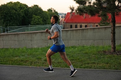 Photo of Athletic young man in sportswear running outdoors