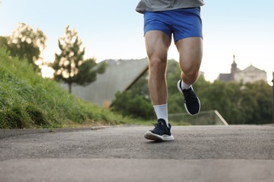 Photo of Athletic young man in sportswear running outdoors, closeup. Space for text