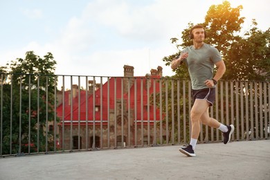 Photo of Athletic young man in sportswear running outdoors, space for text