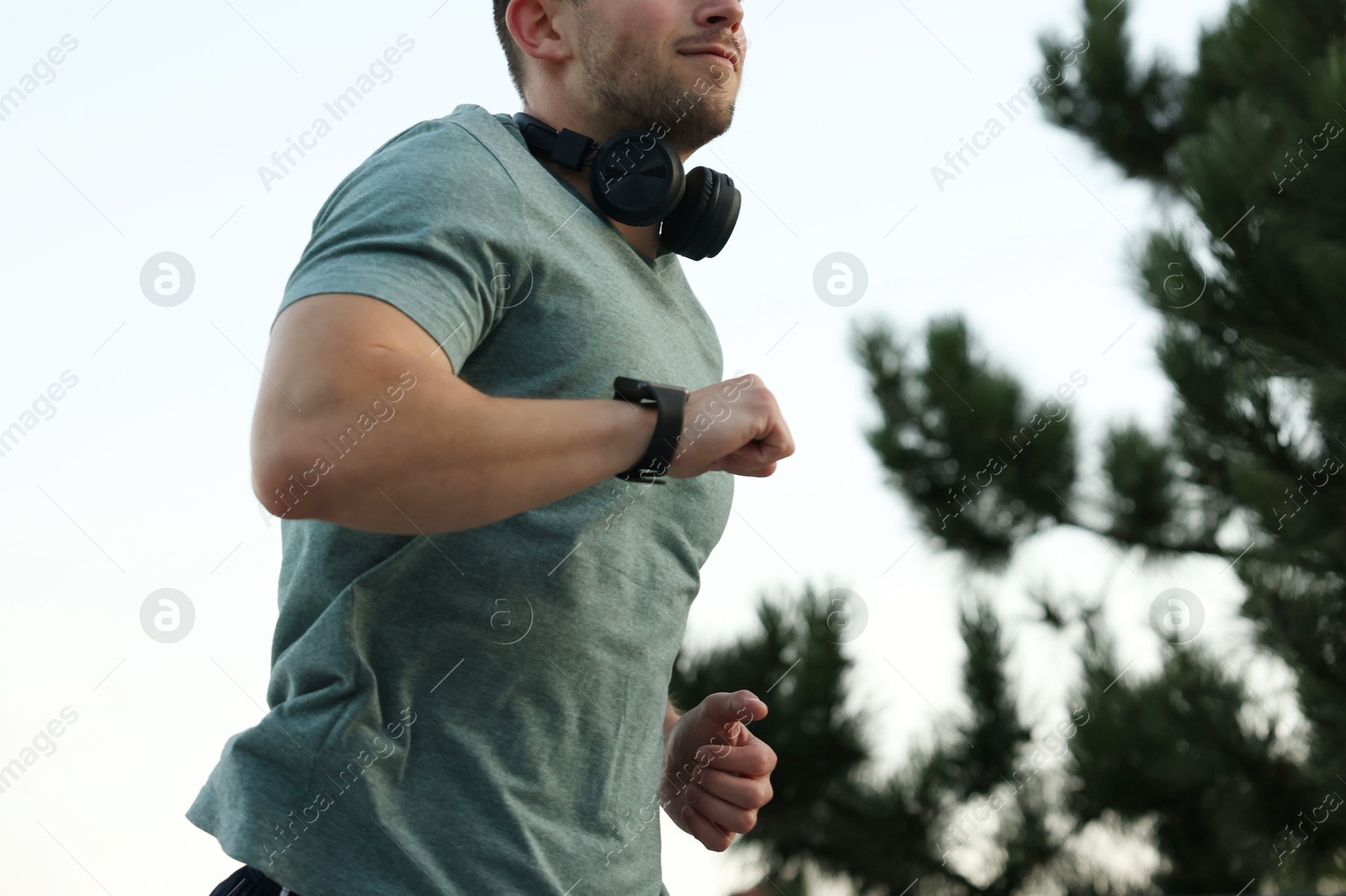 Athletic young man in sportswear running outdoors, closeup Photo of Athletic young man in sportswear running outdoors, closeup
