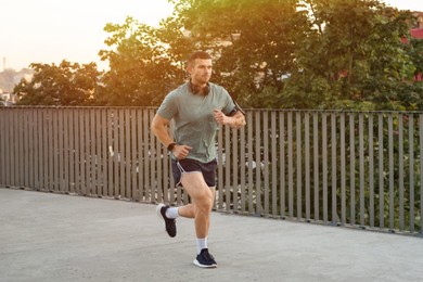 Photo of Athletic young man in sportswear running outdoors