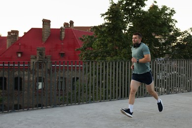 Photo of Athletic young man in sportswear running outdoors, space for text