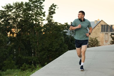 Photo of Athletic young man in sportswear running outdoors, space for text