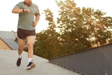 Photo of Athletic young man in sportswear running outdoors, closeup. Space for text