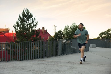 Photo of Athletic young man in sportswear running outdoors, space for text