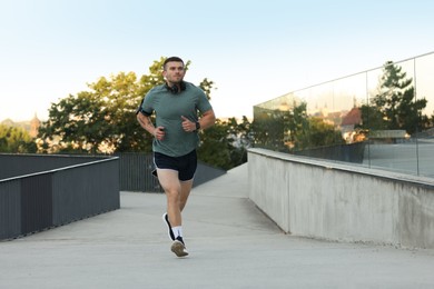 Photo of Athletic young man in sportswear running outdoors