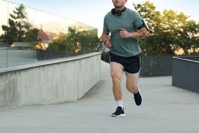 Photo of Athletic young man in sportswear running outdoors, closeup. Space for text