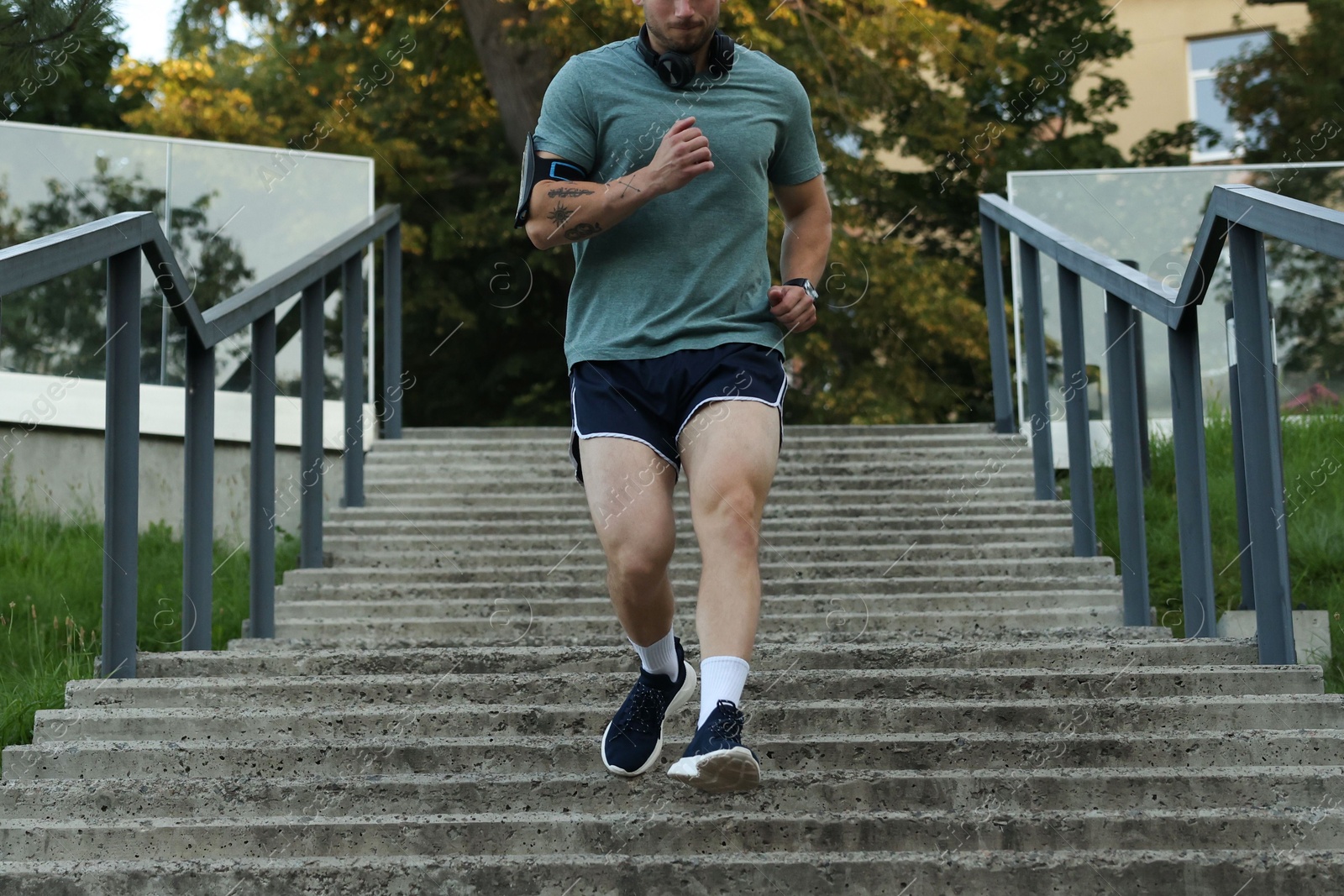 Athletic young man in sportswear running down stairs outdoors, closeup Photo of Athletic young man in sportswear running down stairs outdoors, closeup