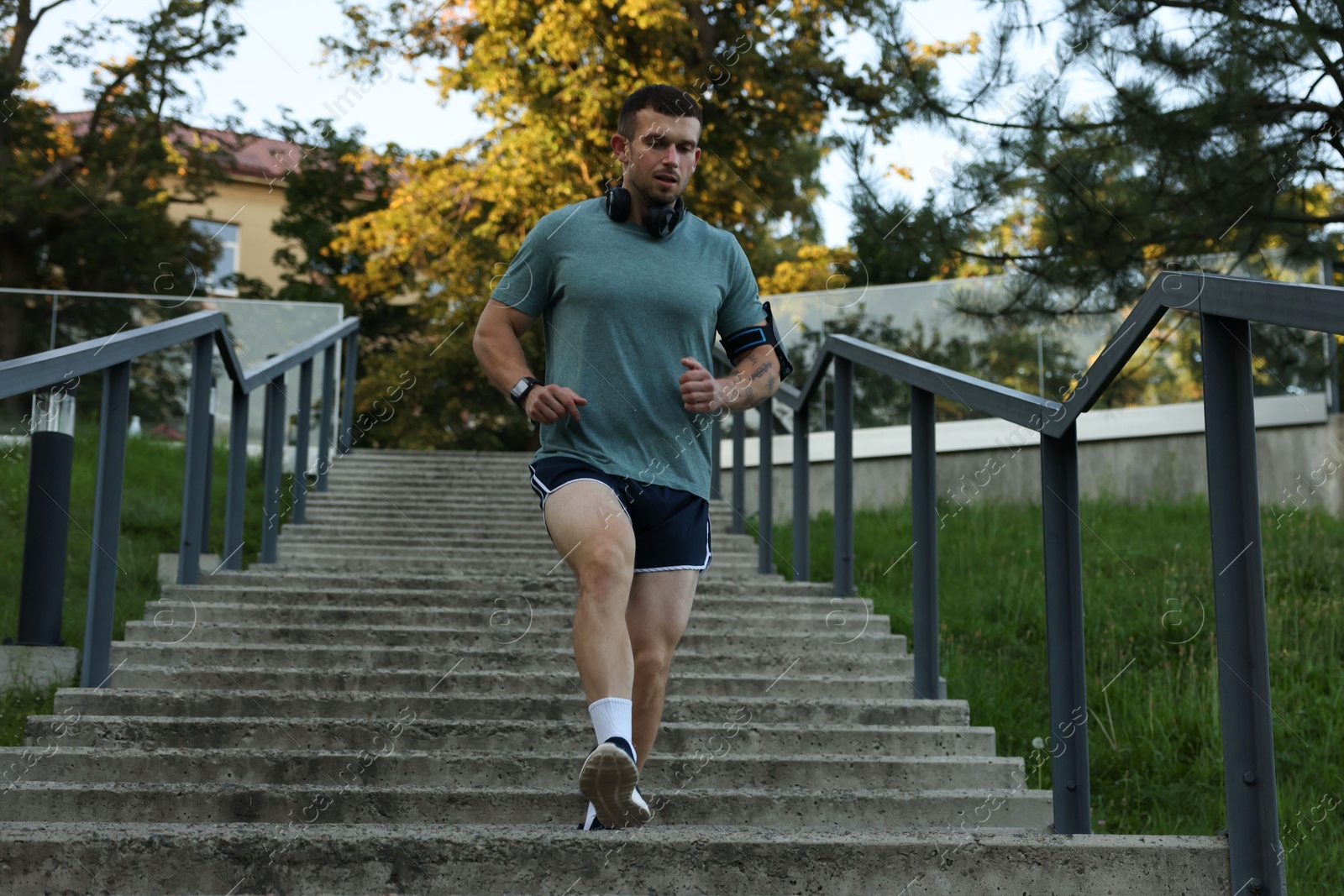 Photo of Athletic young man in sportswear running down stairs outdoors, low angle view