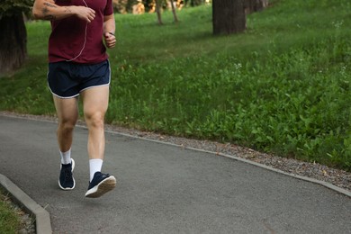 Photo of Athletic young man in sportswear running outdoors, closeup. Space for text