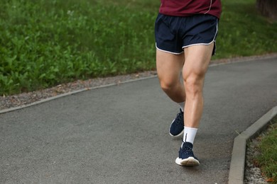 Photo of Athletic young man in sportswear running outdoors, closeup. Space for text