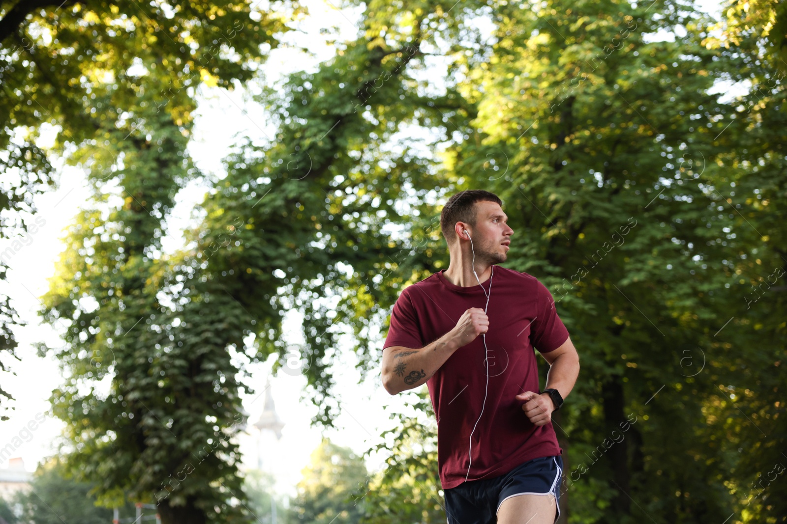 Athletic young man in sportswear running outdoors, space for text Photo of Athletic young man in sportswear running outdoors, space for text