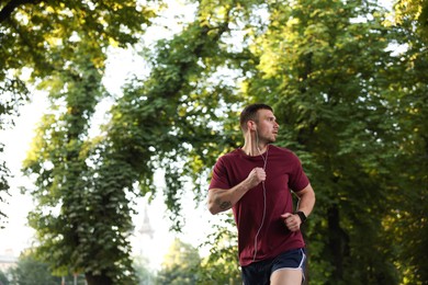 Photo of Athletic young man in sportswear running outdoors, space for text