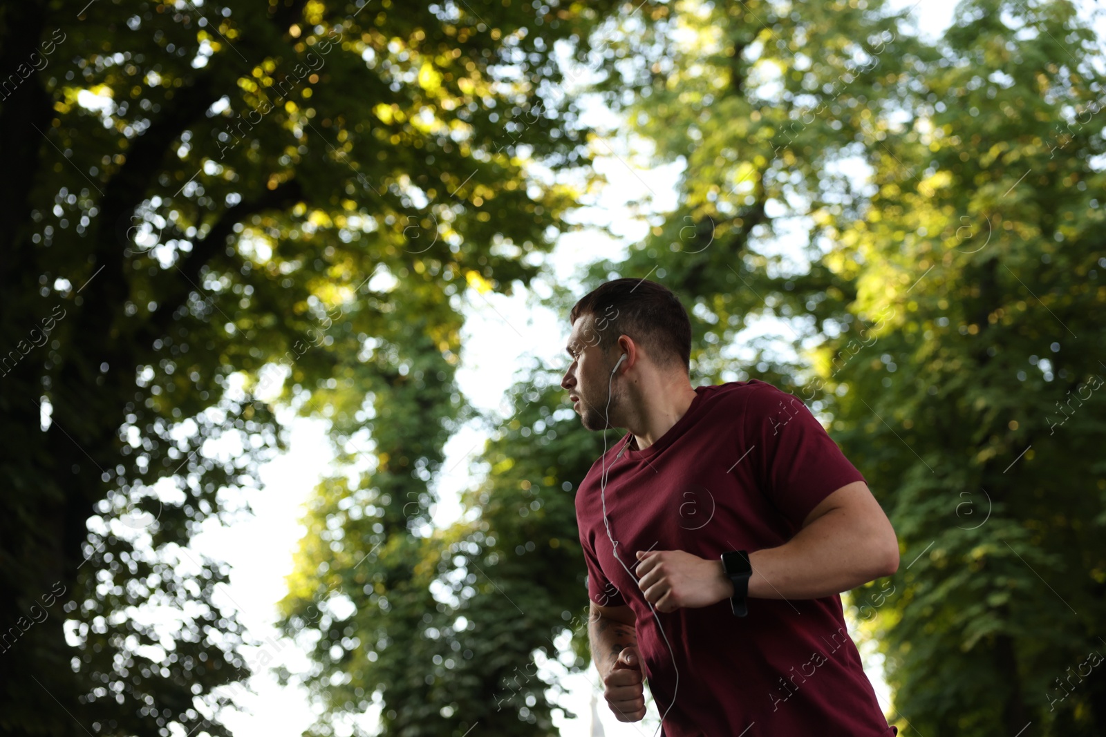Athletic young man in sportswear running outdoors, space for text Photo of Athletic young man in sportswear running outdoors, space for text