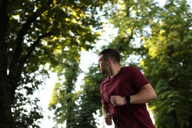 Photo of Athletic young man in sportswear running outdoors, space for text