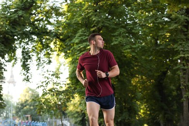 Photo of Athletic young man in sportswear running outdoors