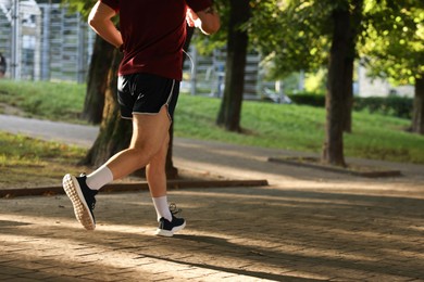 Photo of Athletic young man in sportswear running outdoors, closeup. Space for text