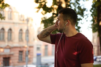 Photo of Athletic young man in sportswear before running outdoors, space for text
