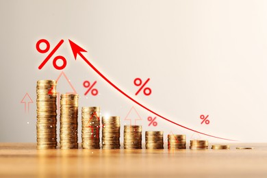 Image of Percent signs and arrows above stacked coins on wooden table against beige background