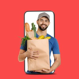 Image of Delivery service worker giving order out of mobile phone against red background. Man with paper bag full of food products