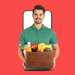 Image of Delivery service worker giving order out of mobile phone against red background. Man with crate full of food products