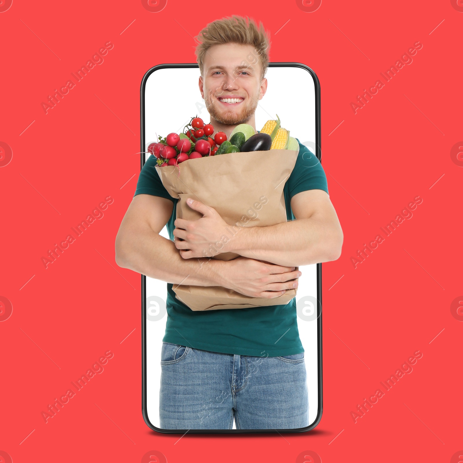 Delivery service worker giving online order out of mobile phone against red background. Man with paper bag full of food products Image of Delivery service worker giving online order out of mobile phone against red background. Man with paper bag full of food products