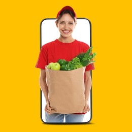 Image of Delivery service worker giving online order out of mobile phone against orange background. Woman with paper bag full of food products