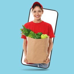 Image of Delivery service worker giving order out of mobile phone against light blue background. Woman with paper bag full of food products