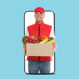 Image of Delivery service worker giving order out of mobile phone against light blue background. Man with box full of food products