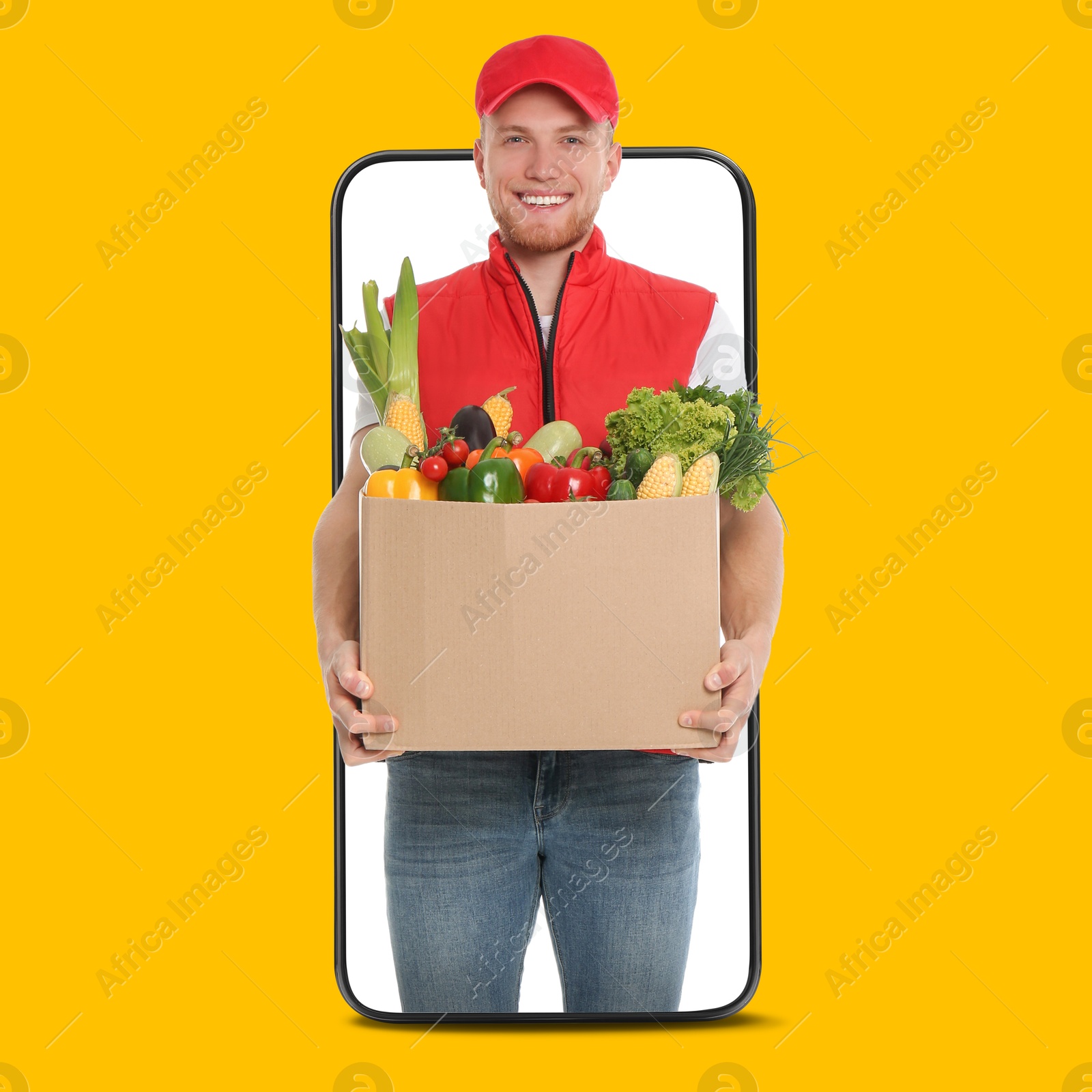 Delivery service worker giving online order out of mobile phone against orange background. Man with box full of food products Image of Delivery service worker giving online order out of mobile phone against orange background. Man with box full of food products