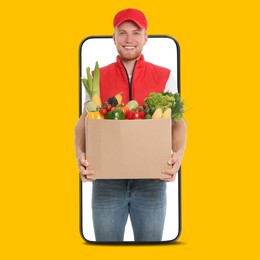 Image of Delivery service worker giving online order out of mobile phone against orange background. Man with box full of food products