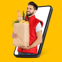 Image of Delivery service worker giving online order out of mobile phone against orange background. Man with paper bag full of food products