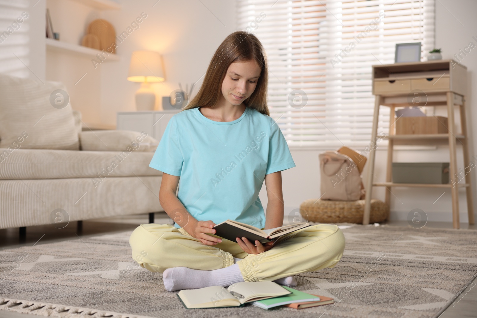 Teenage girl studying with books on floor in room. Homeschooling Photo of Teenage girl studying with books on floor in room. Homeschooling