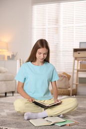 Photo of Teenage girl studying with books on floor at home
